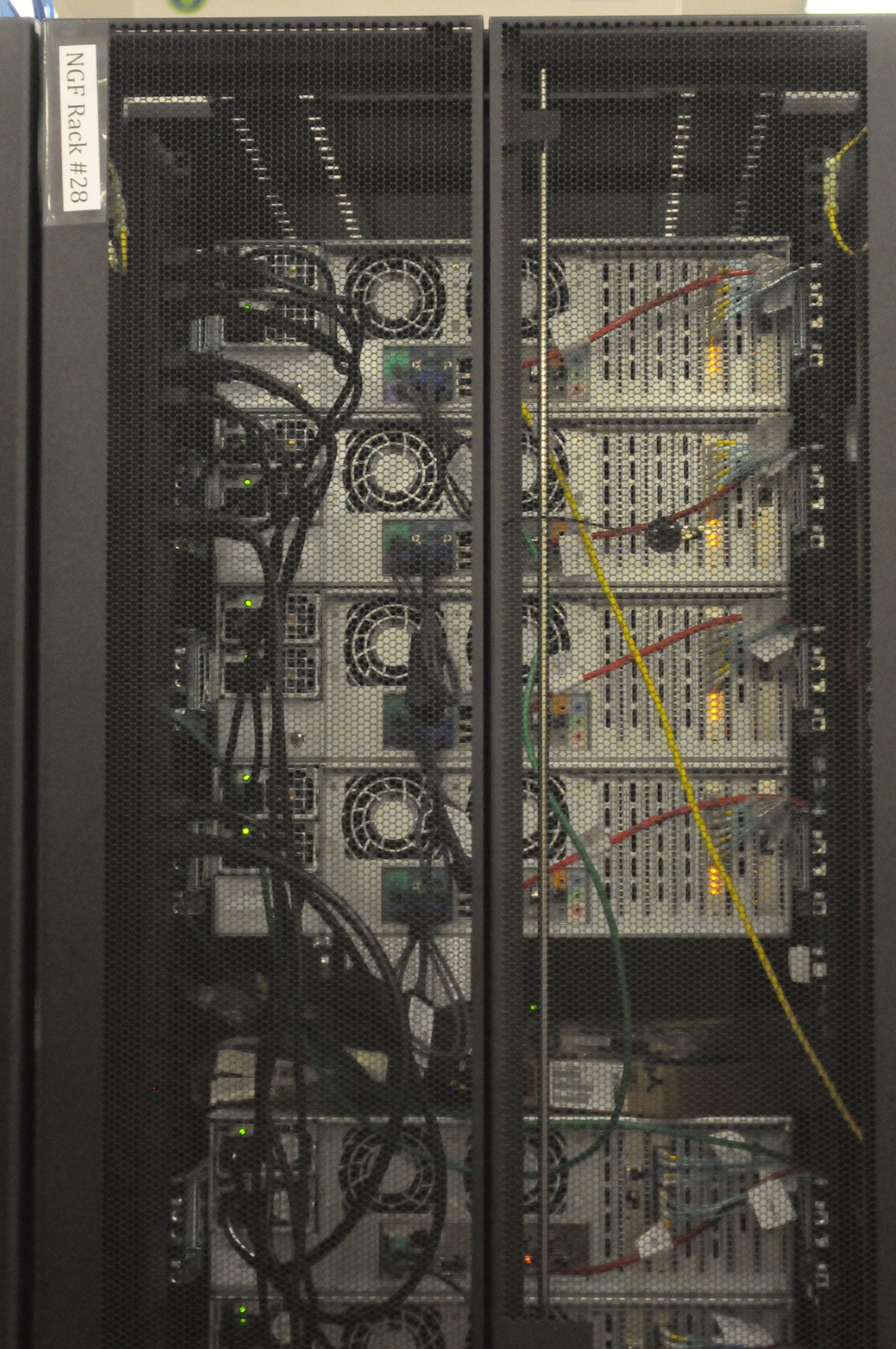 Rückseite eines Serverschranks mit Kabeln und mehreren Rechnern