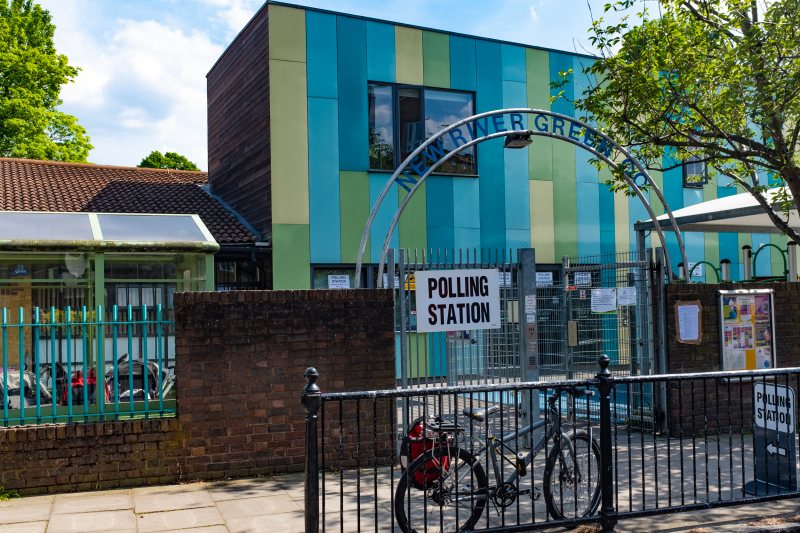 Gebäude eines Wahllokals mit Hinweisschild am Eingang