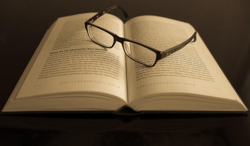 Aufgeschlagenes Buch mit Brille als Symbol für Bildung