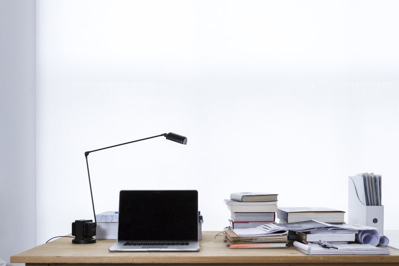 Laptop auf einem Schreibtisch neben mehreren Büchern