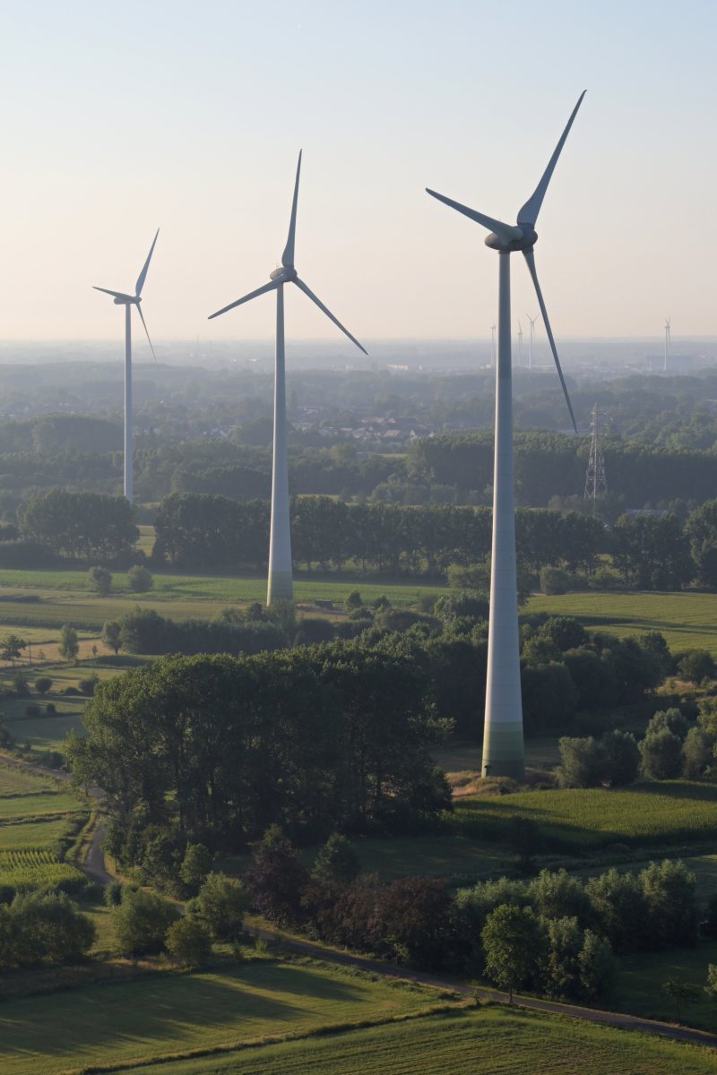 Mehrere Windräder in einer grünen Landschaft aus der Luft gesehen