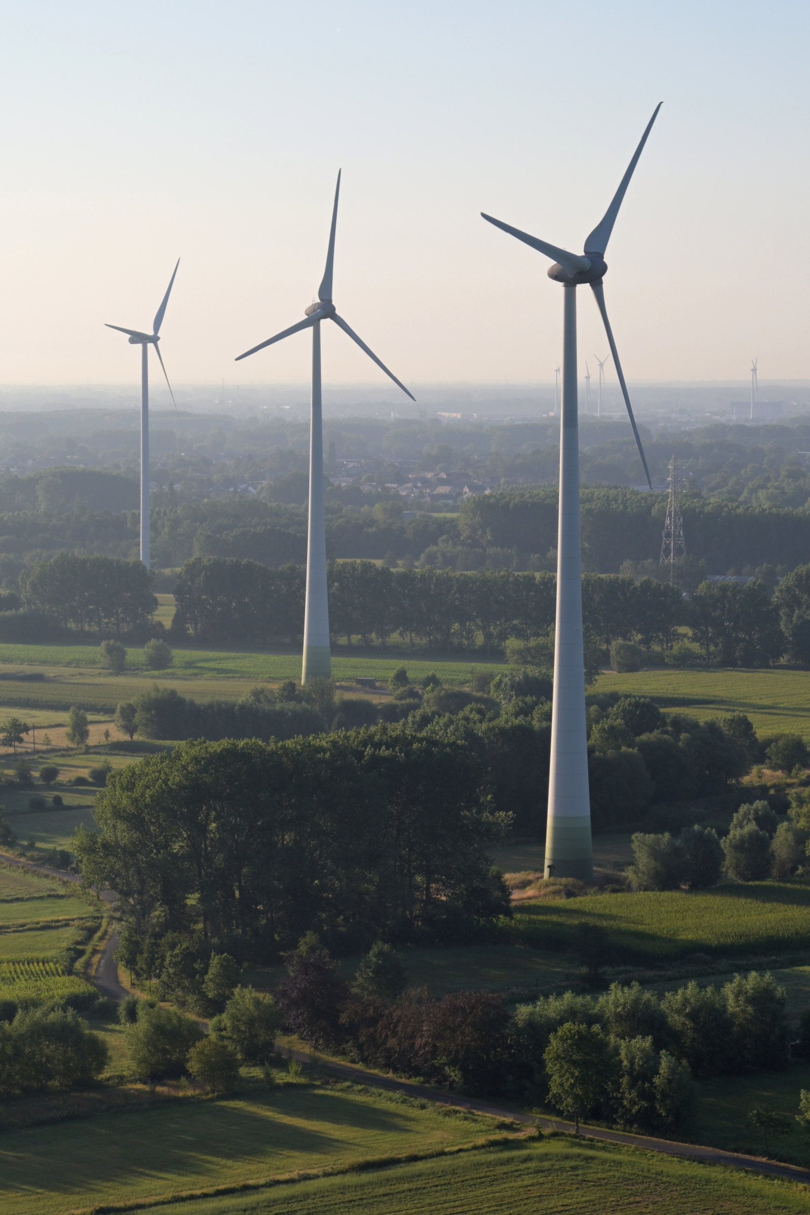 Mehrere Windräder in einer grünen Landschaft aus der Luft gesehen