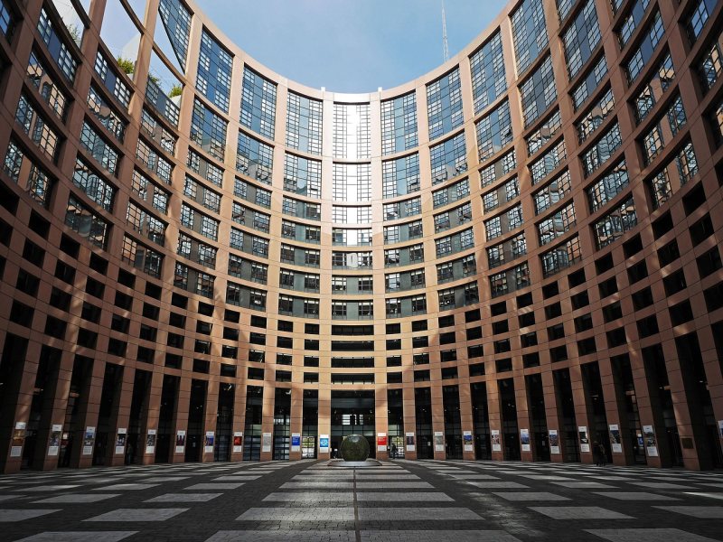 Der Innenhof des Europäischen Parlaments in Straßburg mit gebogener Glasfassade.