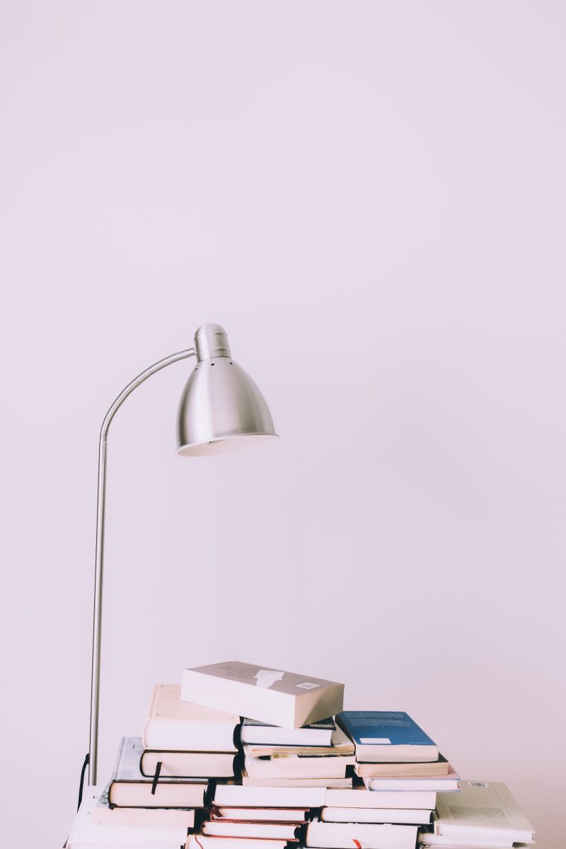 Bücherstapel und Schreibtischlampe als Symbol für Hochschulbildung
