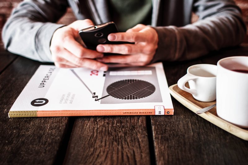 Ein Smartphone liegt neben einer Kaffeetasse auf einem Tisch