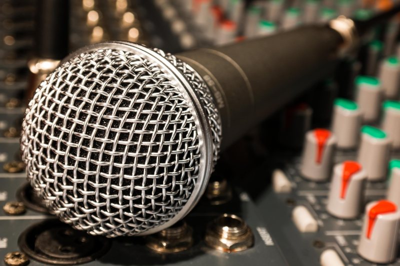 Ein Mikrofon liegt vor einem Audiomischpult.