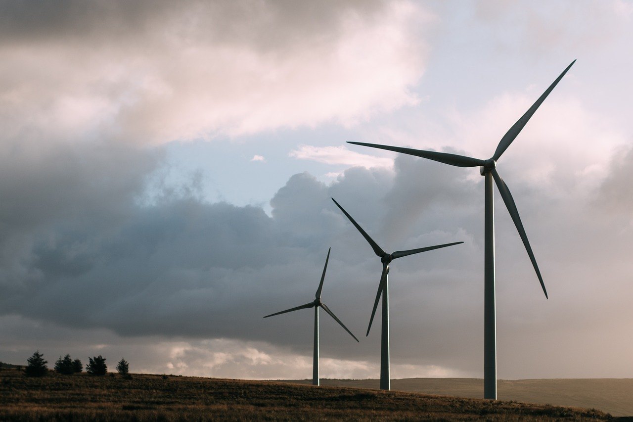 Windkraftanlagen stehen in einer offenen Landschaft